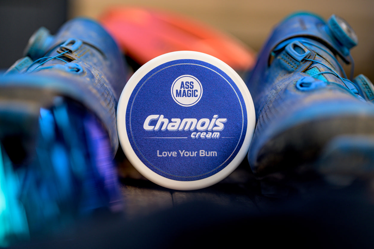 ASS MAGIC Chamois Cream - 200ml Tub laying next to various cycling accessories (cycling shoes)